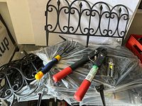 Stack of plastic garden border panels, hand cultivator, ratcheting cutter, small snip