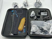 Open case showing floating grip, folding grip, accessory bags, camera area