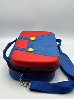 Front angled view of closed case showing Mario color scheme and strap