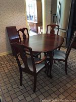 Oval wood dining table with four chairs in kitchen showing shape and style