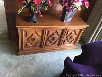 Photo showing front view of wooden cabinet with decorative drawer fronts and items on top