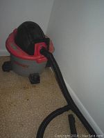 Full view of the Husky wet dry vacuum showing the red and grey body with handle and caster wheels.