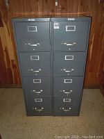Two matching gray Steelmaster metal file cabinets standing side by side against a wood-paneled wall.
