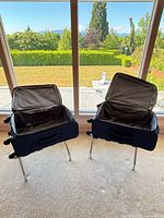 Two navy suitcases open on folding luggage racks