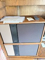 Front view showing both Bose speakers stacked, grilles, manuals and remote on top