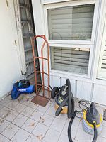 Group shot of compressor, vacuum and hand truck on tiled floor