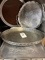 Stacked round woodgrain Formica tray, hammered floral platter, oval pierced gallery tray, square embossed tray