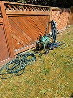 Full view of wheeled hose reel cart with hoses and extra coils on lawn
