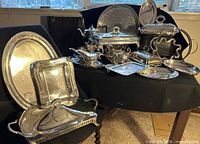 group shot of entire silver-plated serveware lot displayed on chair