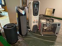 Four appliances grouped: tower air purifier, cylindrical purifier, Soleil oil heater, box fan