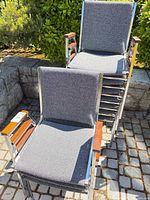 Front view of two chairs showing gray fabric, chrome frame, wood armrests