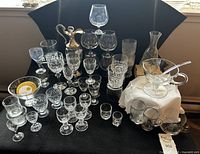 Full lot view showing variety of crystal glasses, claret jug, decanter, carafe, punch bowl with ladle