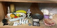 Full shelf view showing majority of items including bakeware, glass fruit, enamel bowl, clock, porcelain pieces, alabaster, shells