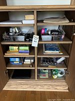Cabinet open showing shelves with organizers and office supplies