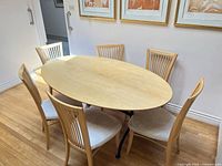 oval light wood dining table with six matching chairs