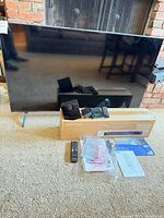 Front view of Samsung TV, boxed soundbar, remotes, manuals and cables