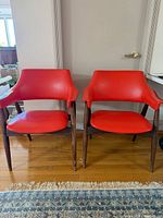 Two red vinyl armchairs side by side on wooden floor