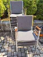 Stack of grey upholstered chrome armchairs outdoors
