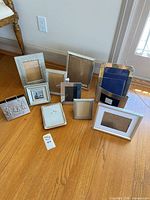 Group of 10 assorted silver metal picture frames on floor