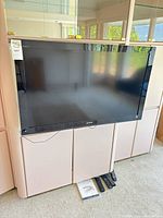 Front view of Sony 40-inch TV with Bose soundbar underneath, remotes and manual visible