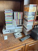 Sony amplifier and CD player below stacked CDs, remote and case visible