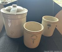 Three crocks displayed, lid on largest, showing markings and relative sizes