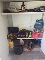 Full cabinet view showing battery charger, tire inflator box, fluids, vacuums and accessories