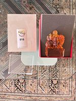 Figurine seated in open box beside acrylic base