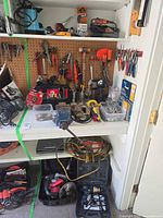 Cabinet with shelves and pegboard showing power tools, hand tools, vise and extension cord