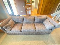 Front view of sofa showing three seat cushions, attached pillow backs, rolled arms, patterned fabric