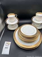 Stacked plates and cups showing gold scroll rim
