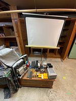 Full setup showing projection screen, projector in case, accessories on table