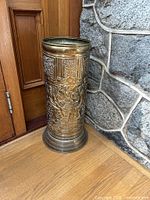 Full view of brass umbrella stand next to wall