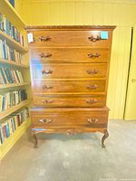 Front view showing six drawers, ornate pulls, cabriole legs