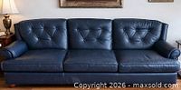 Front view of navy blue three-seat tufted leather sofa