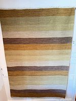 Full view of striped wool Kilim-style rug hung vertically
