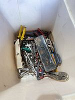 Top view of bin showing mixed hand tools and small metal toolbox