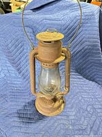 Front view of rusted Beacon hurricane lantern with clear globe and bail handle