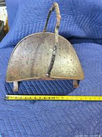 Front view of copper coal scuttle showing curved body, hammered texture, twisted handle, and measuring tape for scale