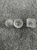 Round crystal dish shown separated into lid and base alongside square dish