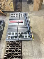 Top view of Delta table saw showing cast-iron tabletop, miter slots, red throat plate, rip fence and power cord