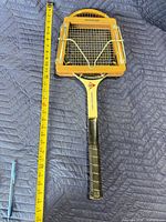 Full view of racket in press with measuring tape showing length
