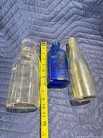 Front view of three bottles beside tape measure