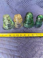 Front view of four glass insulators showing colors and sizes