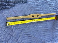 Full view of forged iron bar beside measuring tape showing 19 in. length