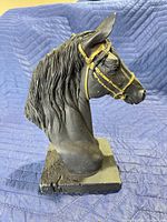 Left front view of black resin horse bust with gold bridle on wood base