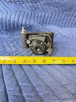 Front view of folded camera with lens extended and tape measure for scale