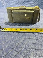Camera folded, front side with Kodak badge and tape measure showing width