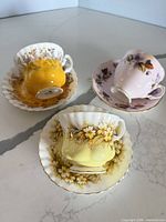 Three inverted teacups on matching saucers showing exterior colours and floral motifs