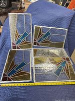 Four fan-motif stained glass panels on blue padding with measuring tape